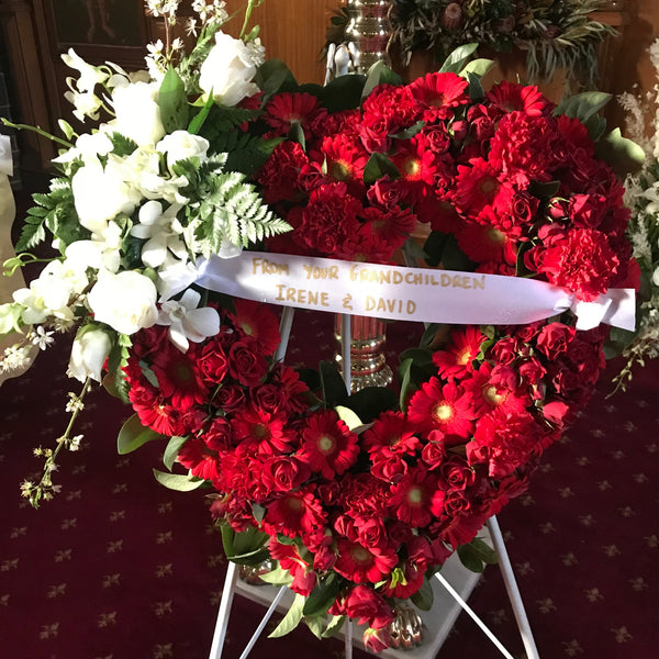 Heart tribute in mixed seasonal reds With a white spray and printed ribbon 